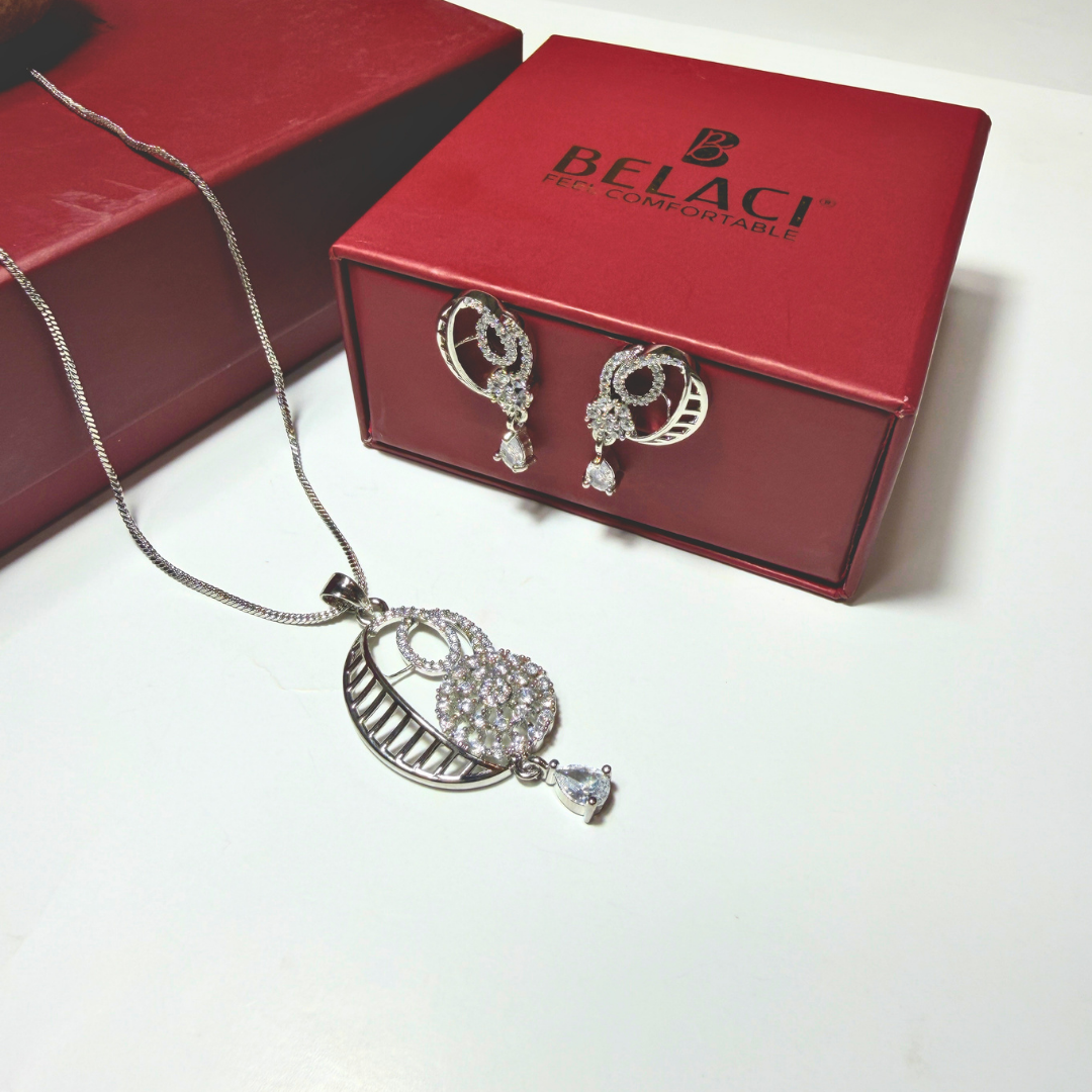 Silver necklace and earrings on a white surface with a red BELACI box in the background.