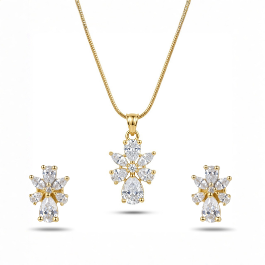 Gold necklace and earrings set with clear gemstones on a white background