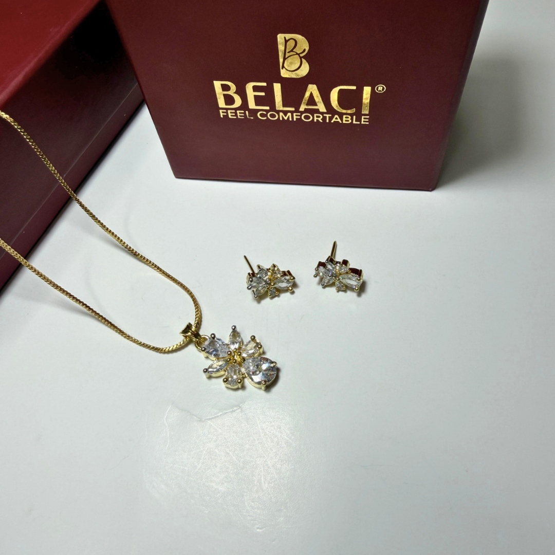 Gold jewelry set with necklace and earrings on a white surface, Belaci brand visible.