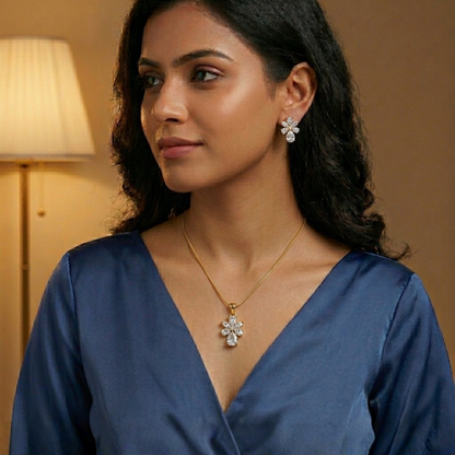Woman wearing a blue top with jewelry, including earrings and a necklace, in a warm-toned room.