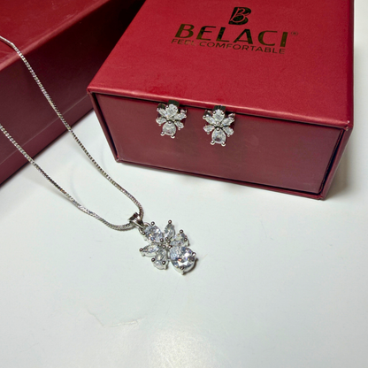 Silver jewelry set with necklace and earrings on a white surface, Belaci box in the background.