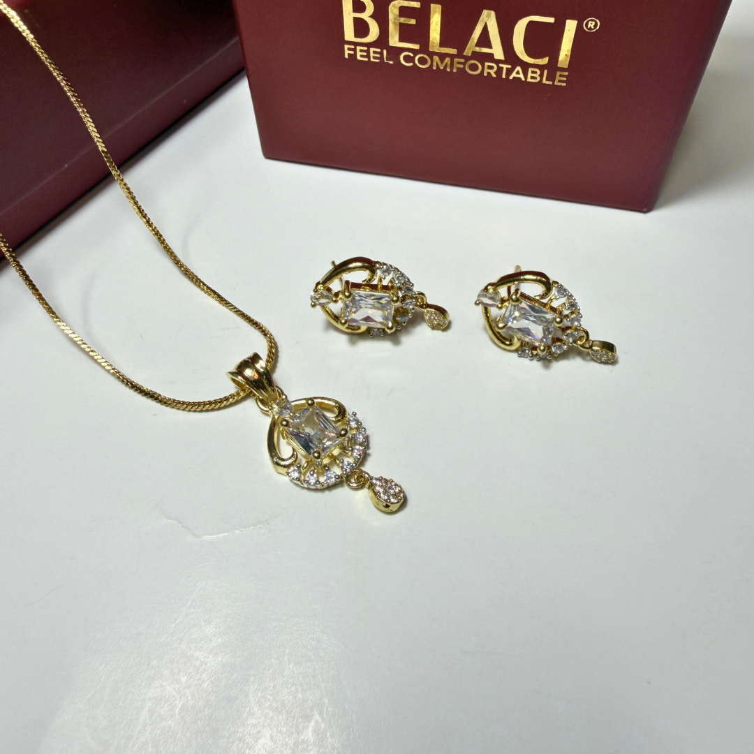 Gold jewelry set with pendant and earrings on a white surface, Belaci brand visible.