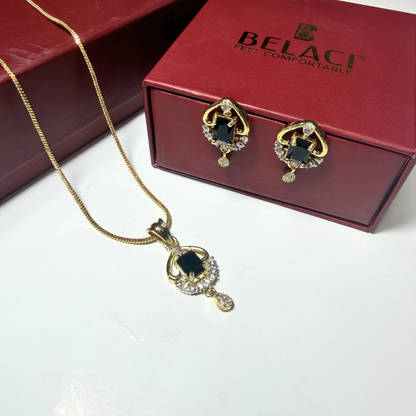 Gold necklace and earrings with black stones on a white surface, Belaci box in the background.