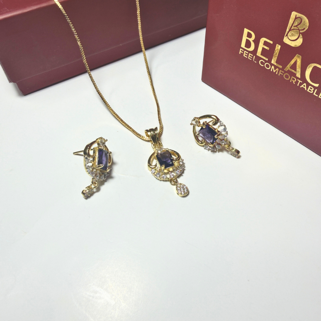 Jewelry set with necklace and earrings on a white surface with a Belac box in the background.