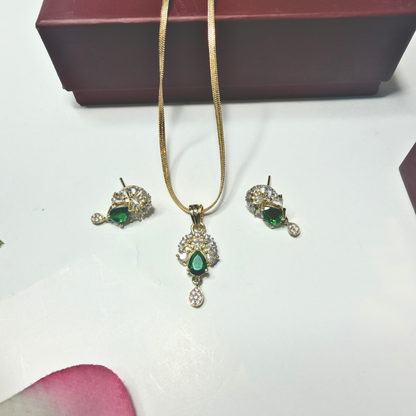Jewelry set with pendant and earrings featuring green gemstones on a white surface.