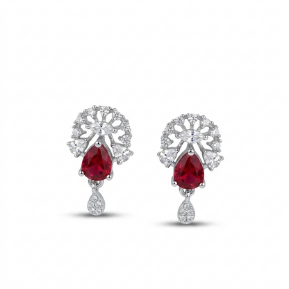 Pair of earrings with red gemstones and silver floral designs on a white background