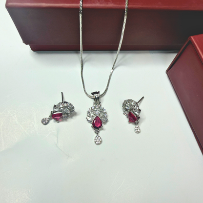 Jewelry set with red gemstones and silver chains on a white surface.