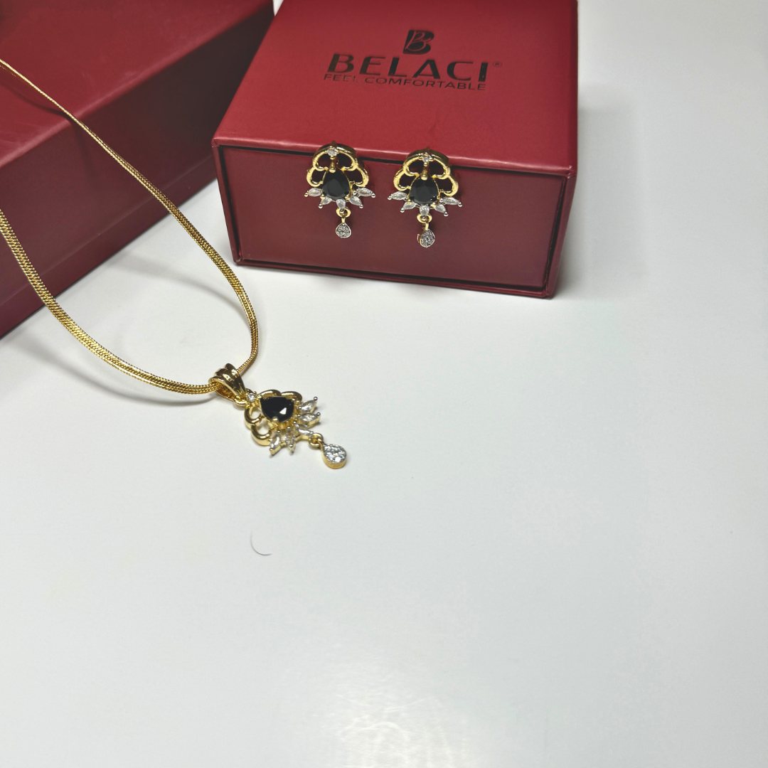 Gold necklace and earrings with black stones in front of a Belaci box on a white background