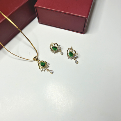 Jewelry set with necklace and earrings featuring green gemstones on a white surface.