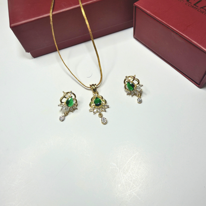 Gold jewelry set with green gemstones on a white surface, with a red box in the background.