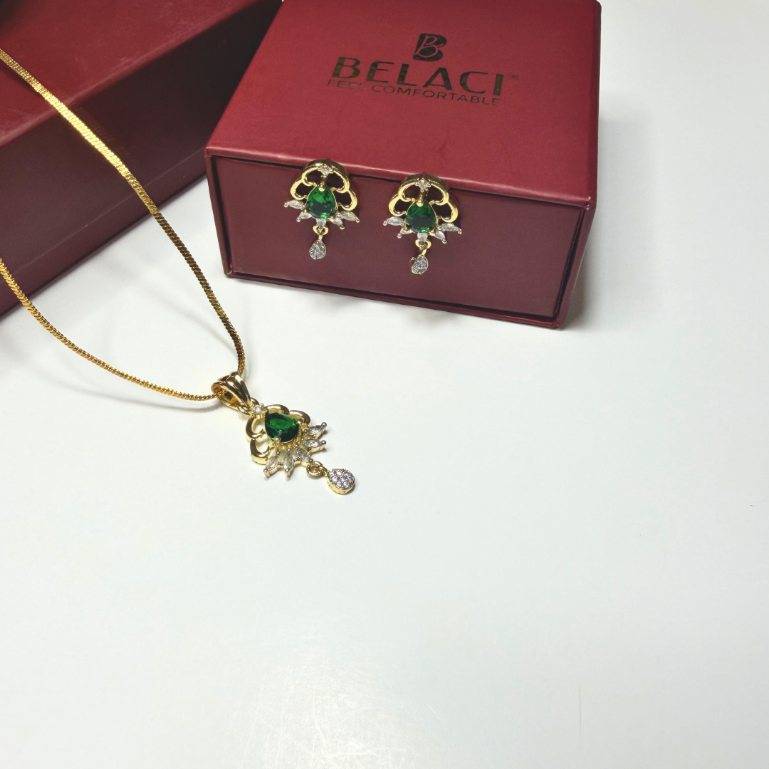 Gold necklace and earrings with green gemstones in front of a Belaci box on a white background