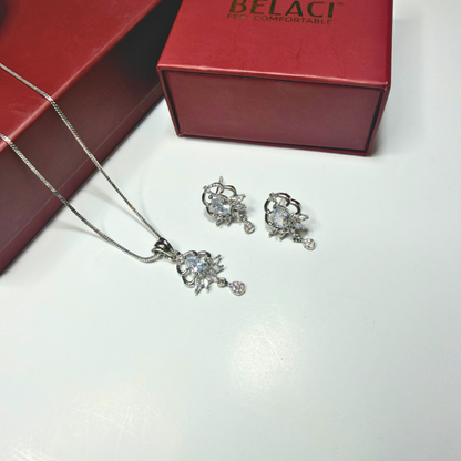 Silver jewelry set with necklace and earrings on a white surface, Belaci box in the background.