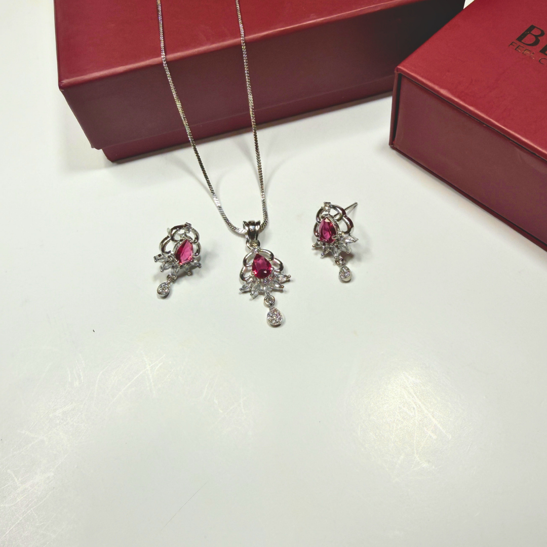 Jewelry set with necklace and earrings on a white surface with a red box in the background.