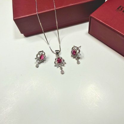 Jewelry set with necklace and earrings on a white surface with a red box in the background.
