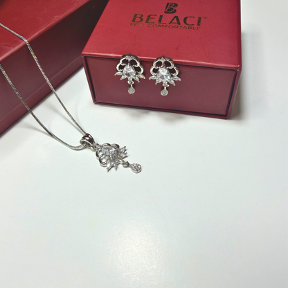Silver jewelry set with necklace and earrings on a white surface, Belaci box in the background.