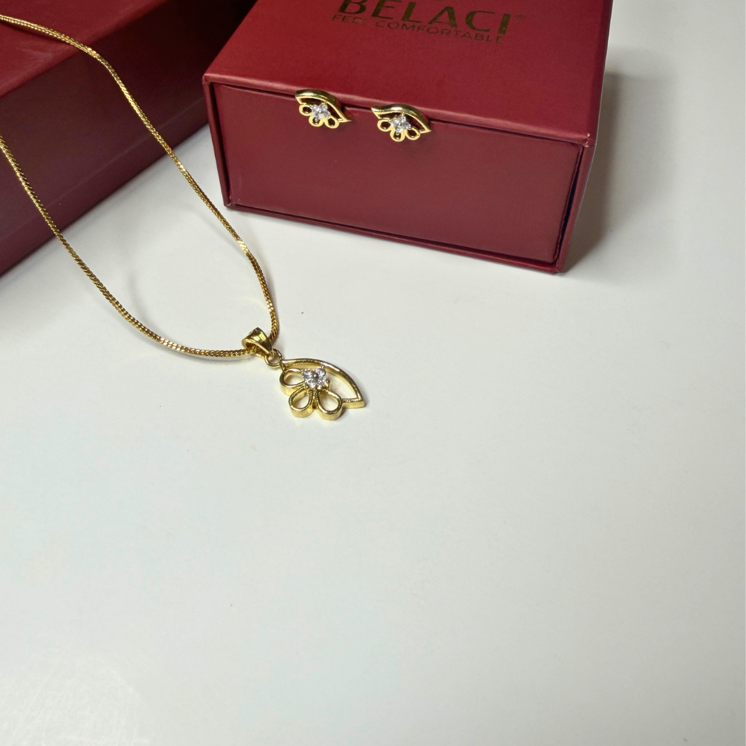Gold necklace with pendant in front of a red Belagi box on a light gray background