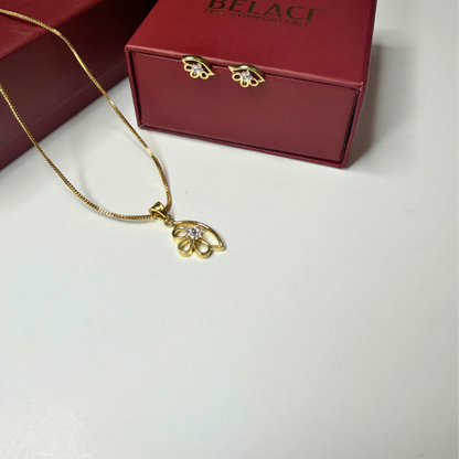 Gold necklace with pendant in front of a red Belagi box on a light gray background