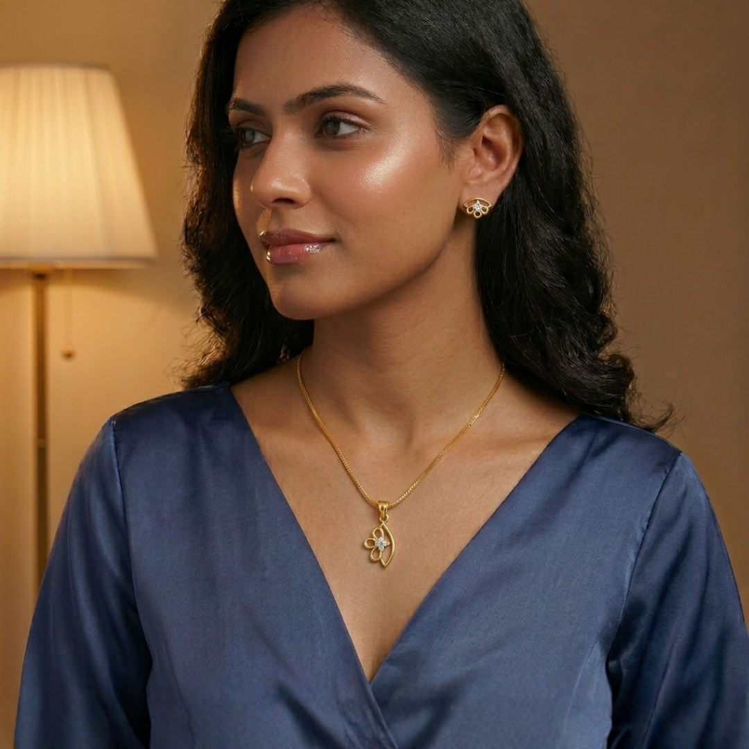 Woman wearing a gold necklace and earrings in a warm-toned room.
