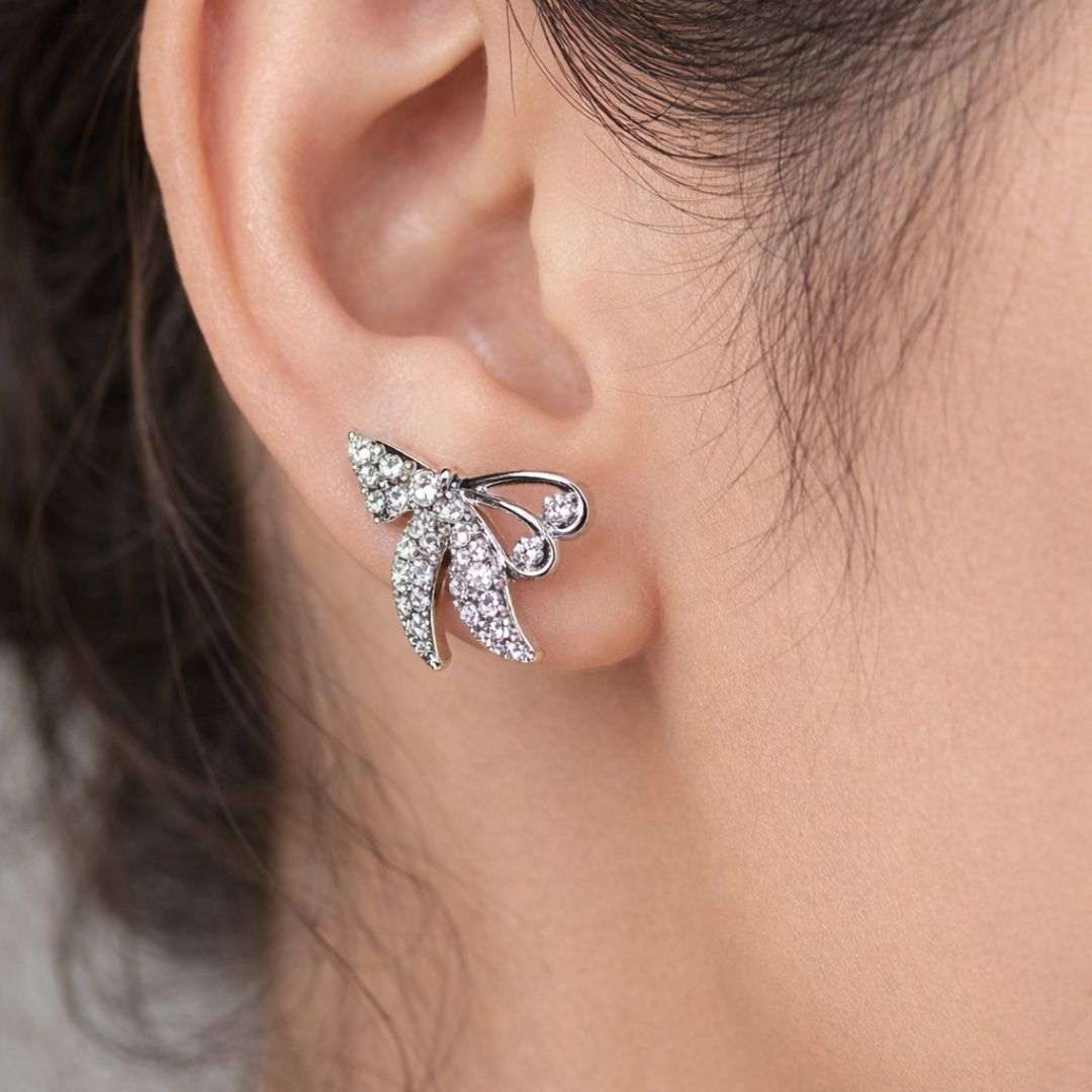 Close-up of a silver leaf-shaped earring worn by a person.