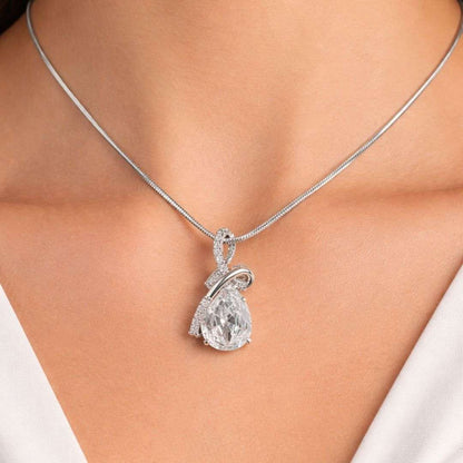 Silver necklace with a pear-shaped diamond pendant on a person wearing a white top.