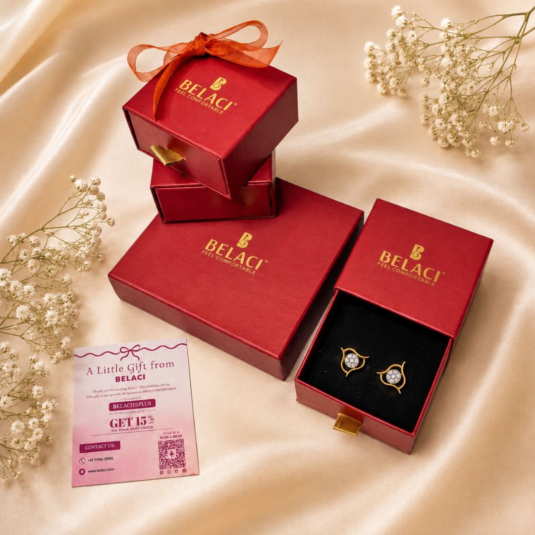 Gold diamond earrings in red Belaci gift boxes with a discount card and baby breath flowers on silk fabric