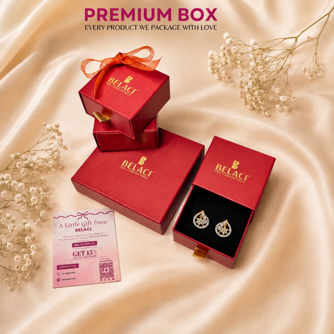 Red Belaci jewelry gift boxes arranged on beige satin fabric with dried baby's breath flowers. One open box displays silver-toned earrings on a black insert, and a pink promotional card is placed nearby.