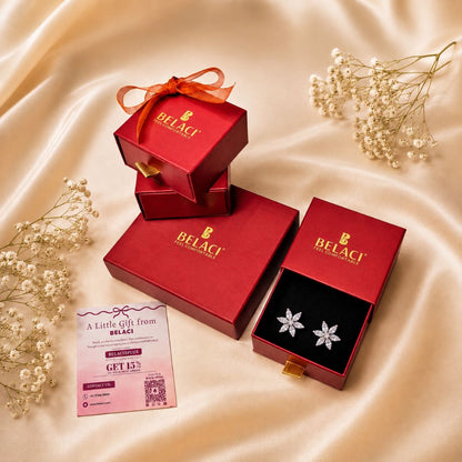 Flower shaped diamond earrings in red Belaci jewelry boxes with a discount card on a silk background