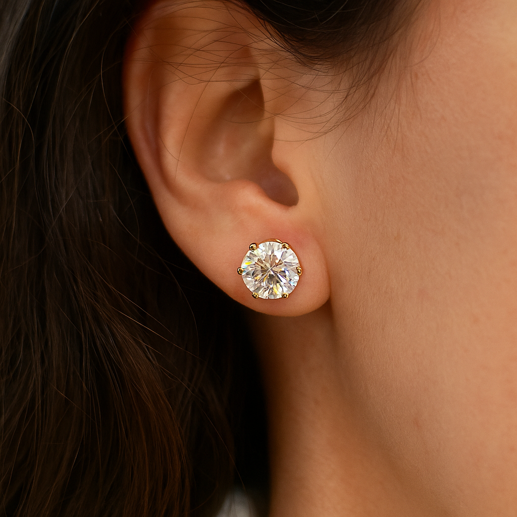 Close-up of an ear wearing a gold Earrings for Women with a clear gemstone.