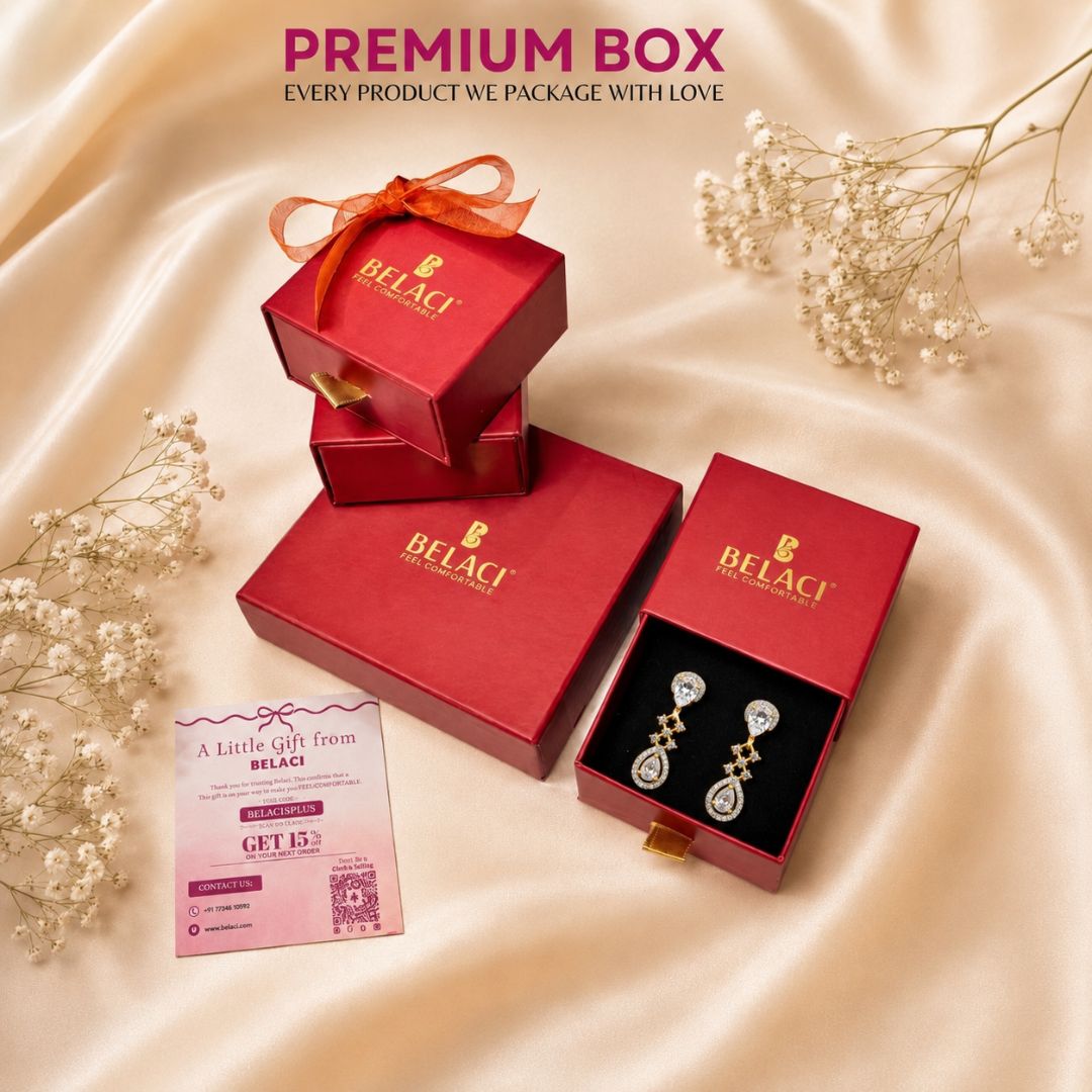 Red jewelry gift boxes with gold logo and dangling crystal earrings on a beige fabric background
