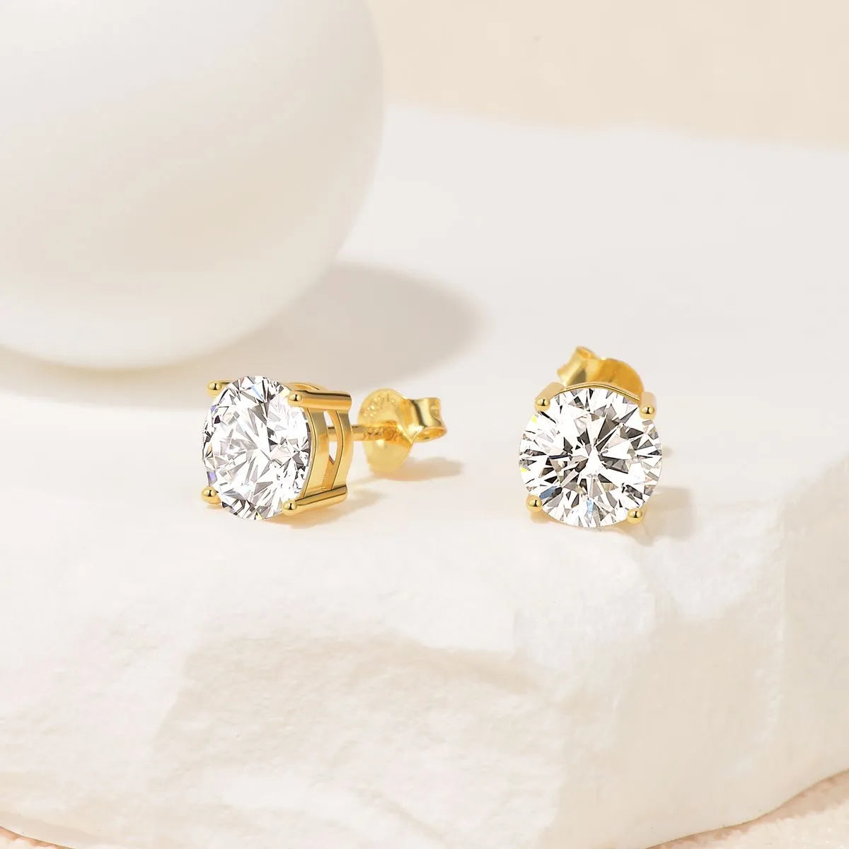 Gold stud earrings for Women with clear gemstones on a light background