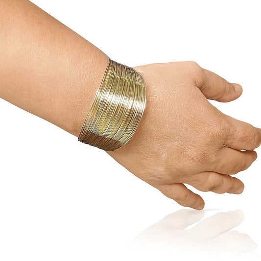 Hand wearing a gold bracelet on a white background