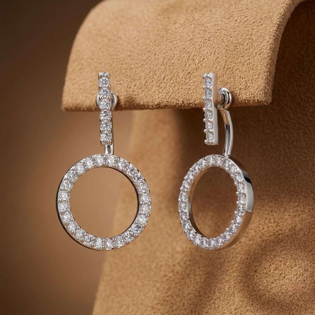 Silver hoop earrings with clear stones on a beige background