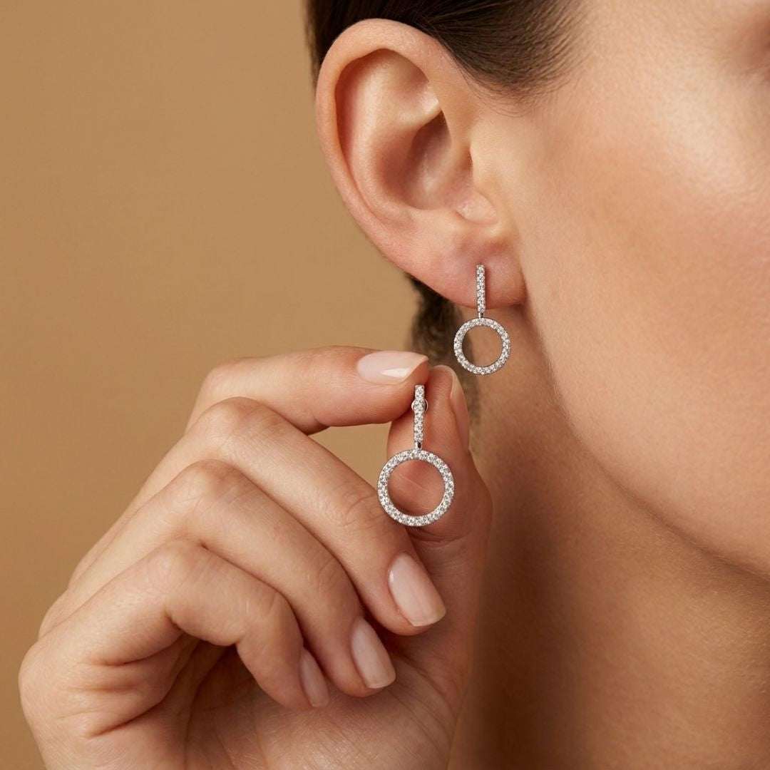 Close-up of a woman wearing silver hoop earrings against a brown background
