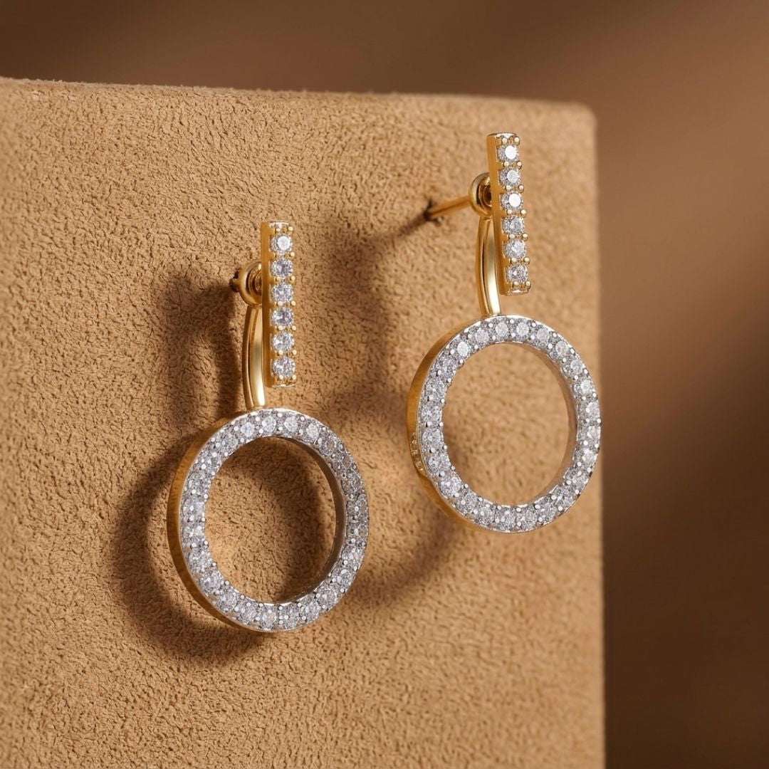 Gold and silver hoop earrings on a beige surface with a brown background