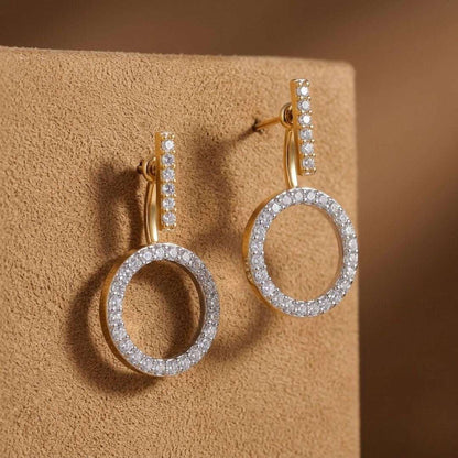 Gold and silver hoop earrings on a beige surface with a brown background