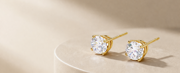 Gold stud earrings with clear gemstones on a white background