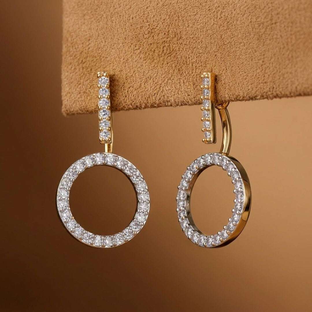 Gold hoop earrings with diamond accents on a brown background