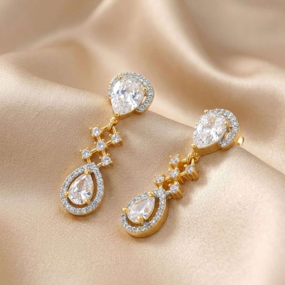 Gold and diamond earrings on a beige fabric background