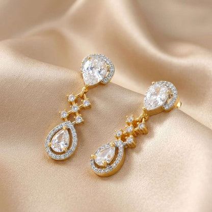 Gold and diamond earrings on a beige fabric background