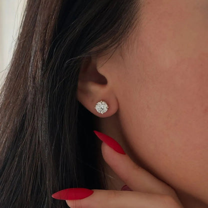 Close-up of an ear wearing a diamond earring with a hand touching the hair.