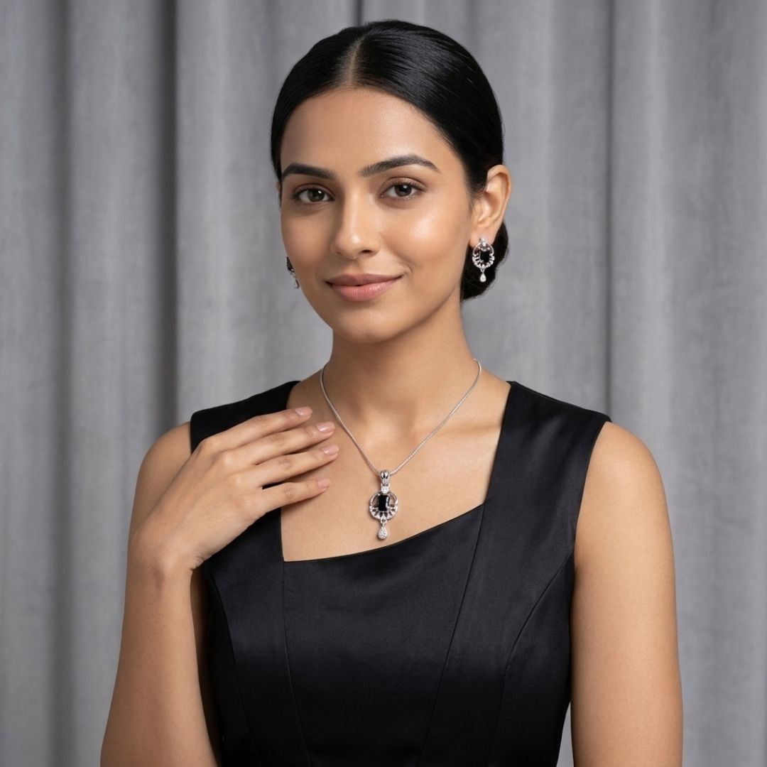 Woman wearing a silver necklace with a black stone pendant and matching drop earrings
