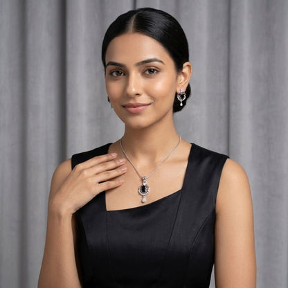 Woman wearing a silver necklace with a black stone pendant and matching drop earrings