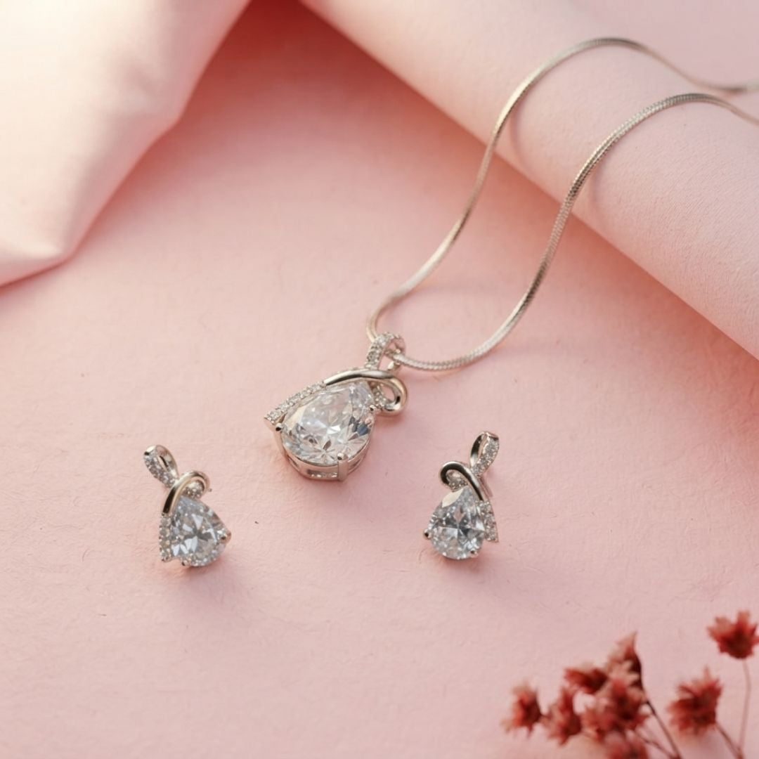 Silver necklace and earring set with pear shaped cubic zirconia stones on pink fabric
