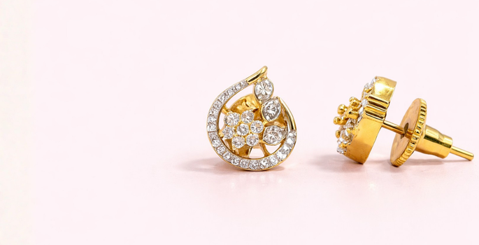 Pair of butterfly-shaped earrings with clear stones on a light pink background