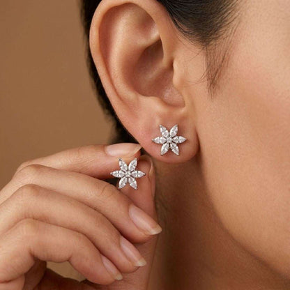 Close-up of a person wearing star-shaped diamond earrings with a neutral background