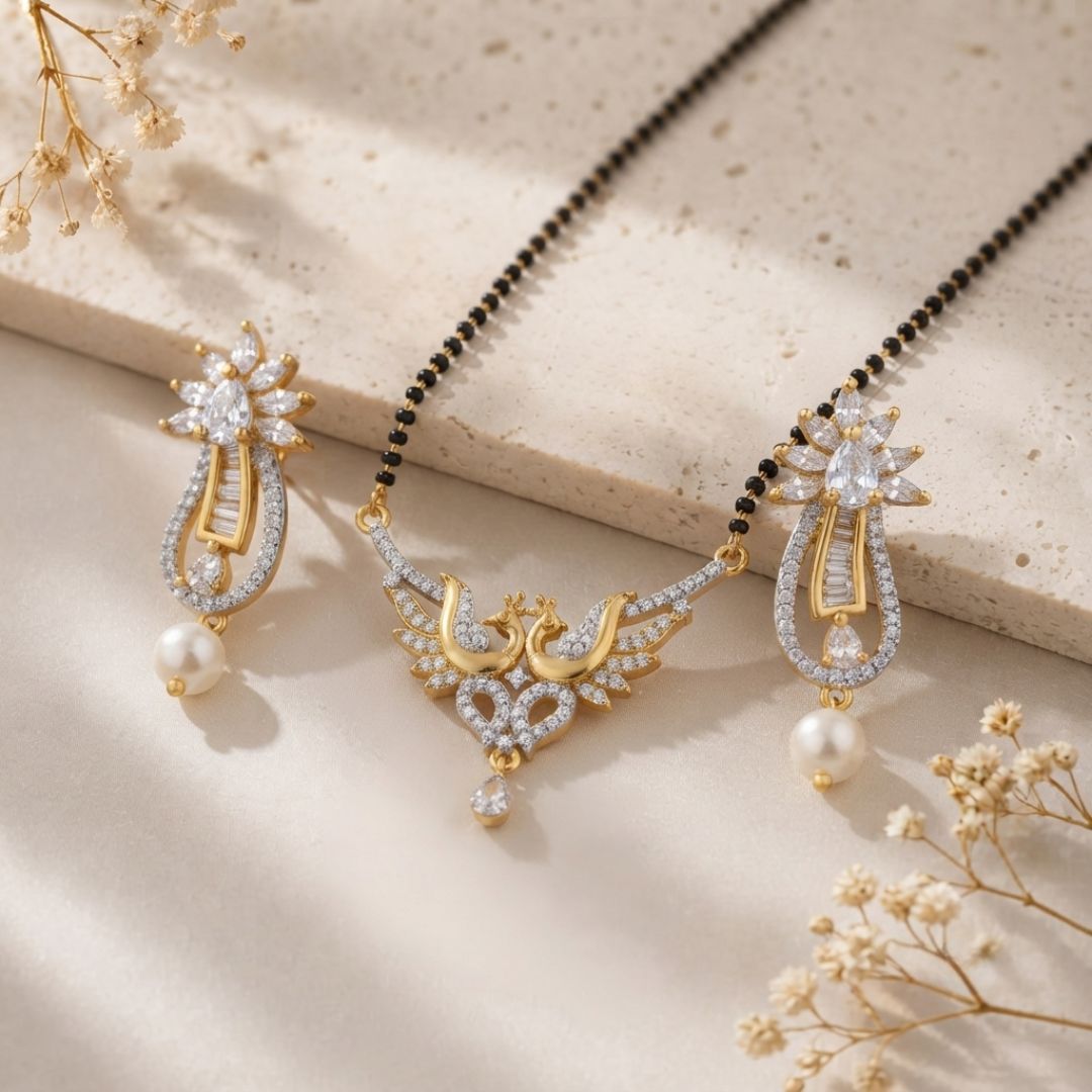 Gold and silver jewelry set with a necklace and matching earrings, decorated with clear crystals and white pearl drops, styled on a beige stone slab with dried flowers.