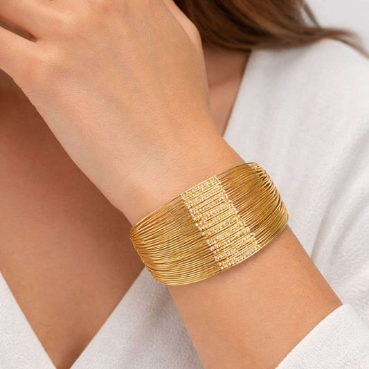 Gold bracelet on a person's wrist with a white background