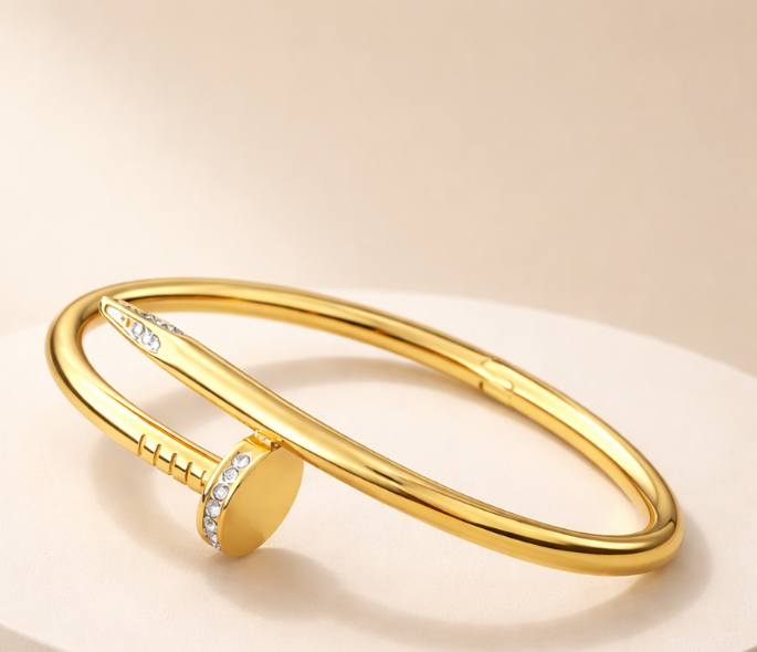 Gold bracelet with a round charm on a beige background