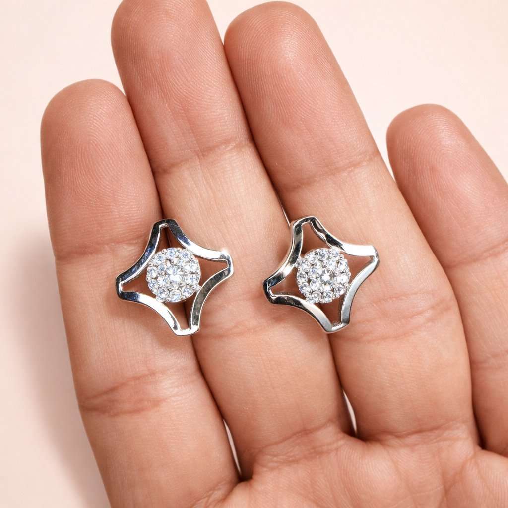 Silver AD Earrings for Women with clear stones held between fingers on a light pink background