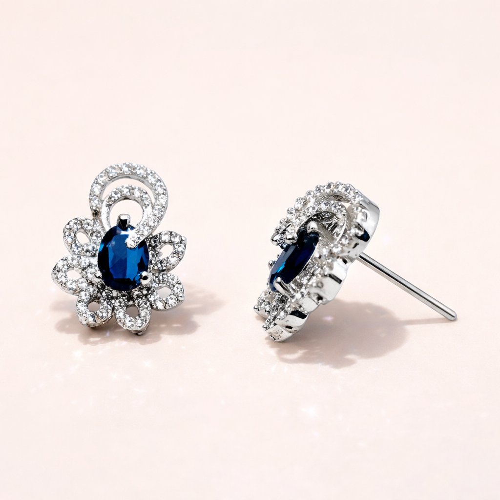 Pair of silver AD Earrings for Women with blue gemstones on a light pink background